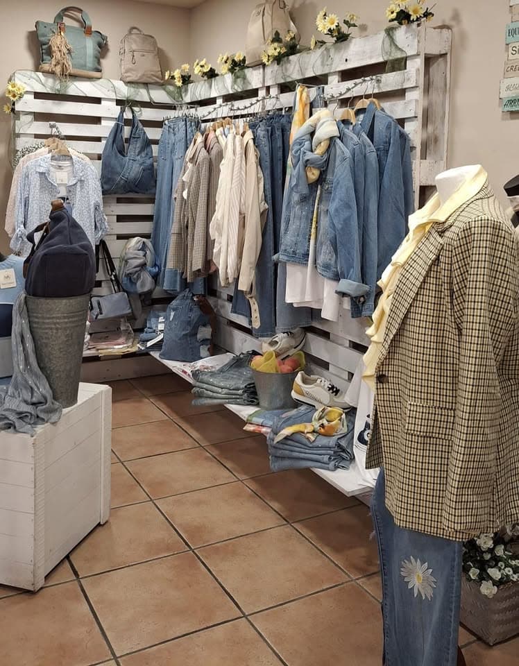 Interior de Top Moda Jove con vaqueros, camisas y bolsos colgados